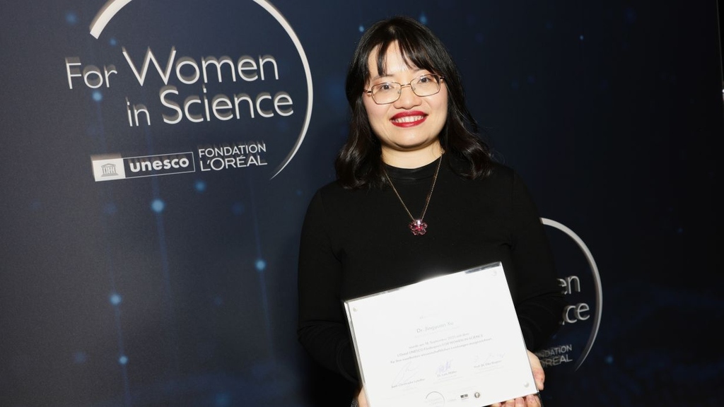 Woman holding a certificate at the For Women in Science UNESCO L'Oréal event.